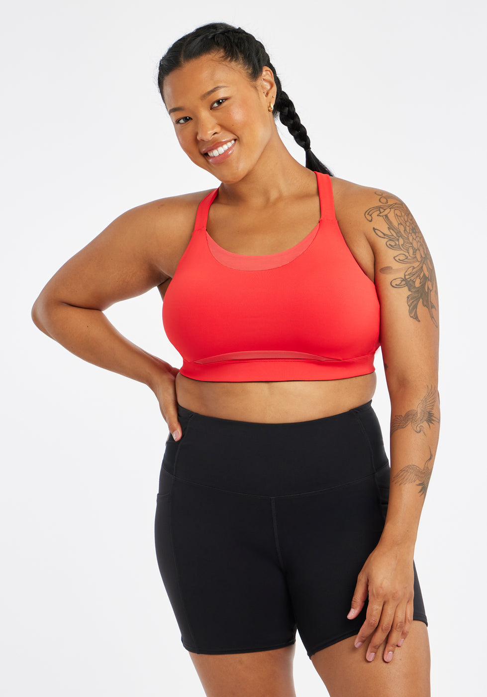 Woman wearing red orange band and cup sports bra, front view