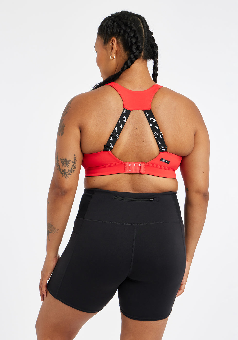 Woman wearing red orange band and cup sports bra, back view