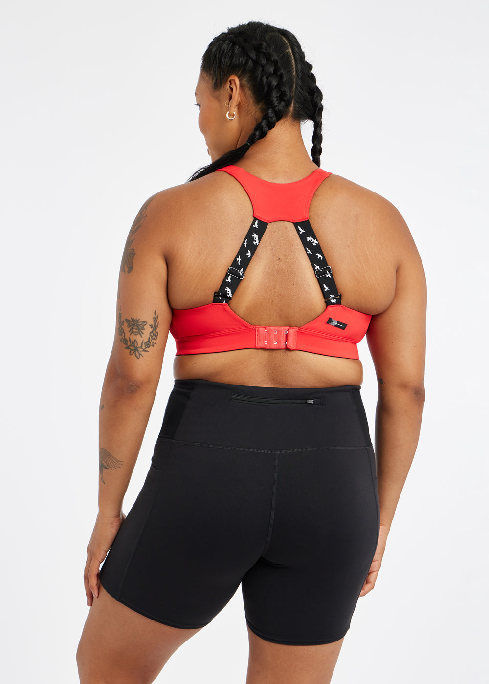 Woman wearing red orange band and cup sports bra, back view