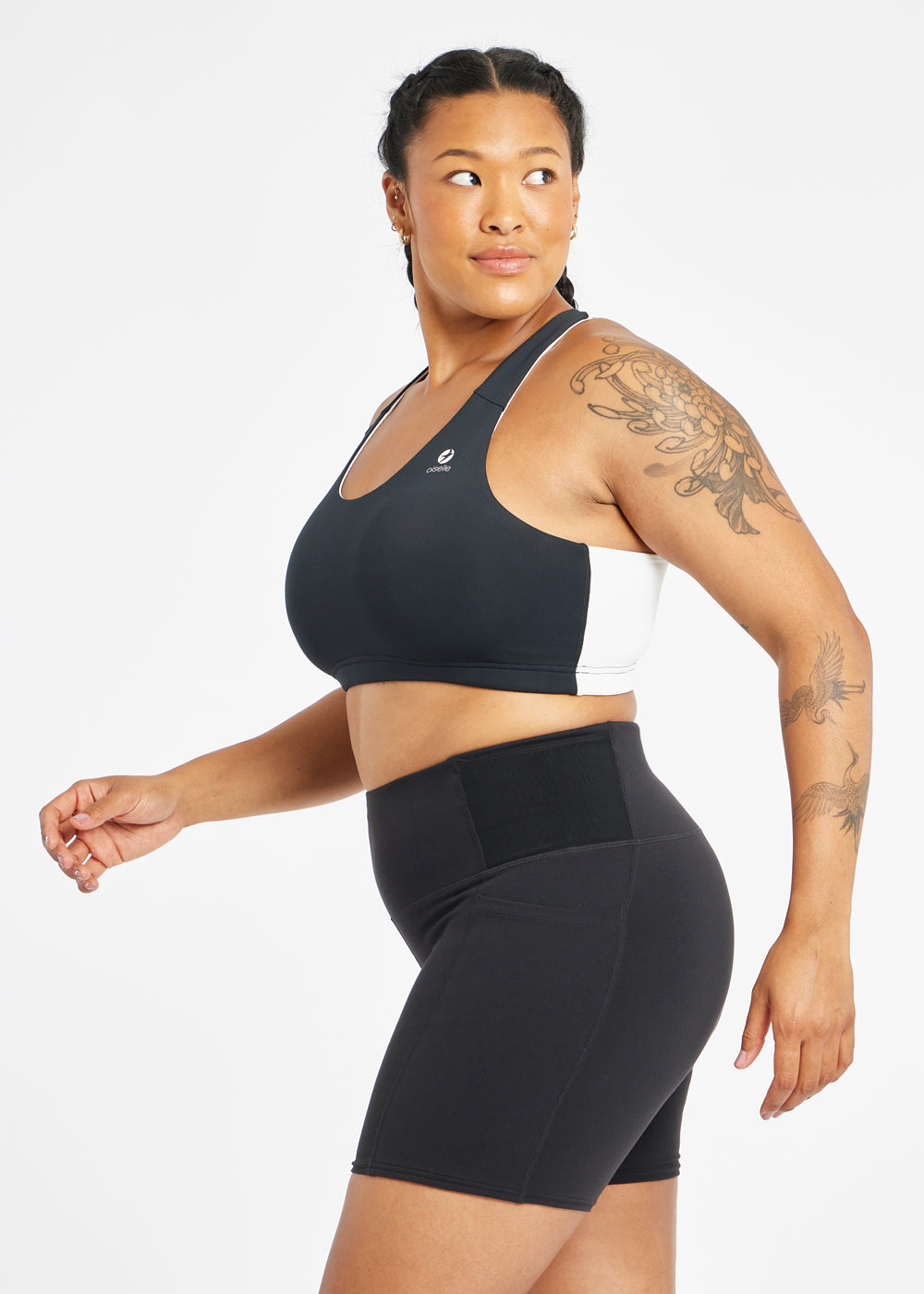 Woman wearing black and white paneled sports bra, side view