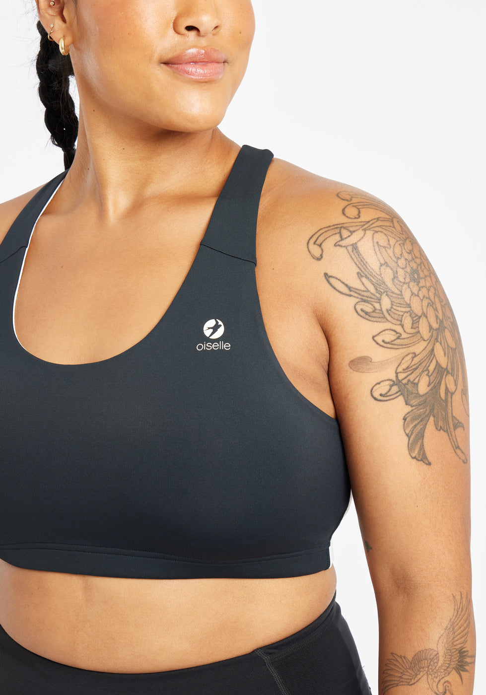 Woman wearing black and white paneled sports bra, close up view of Oiselle branding on chest