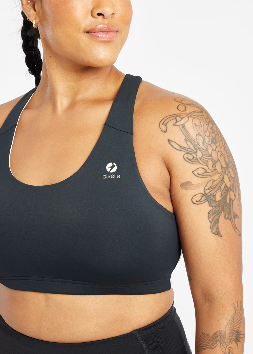 Woman wearing black and white paneled sports bra, close up view of Oiselle branding on chest