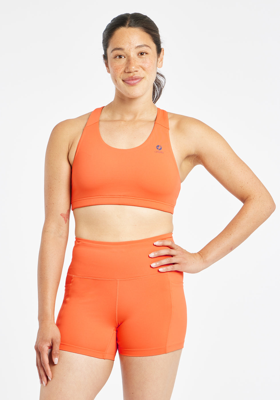 Woman wearing orange and purple paneled sports bra, front view