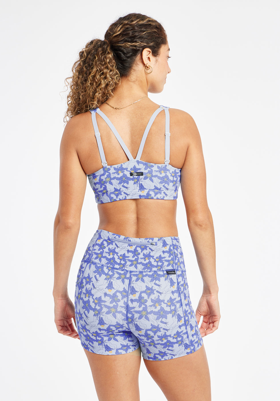 Woman wearing blue with blue floral print sports bra in size 6, back view