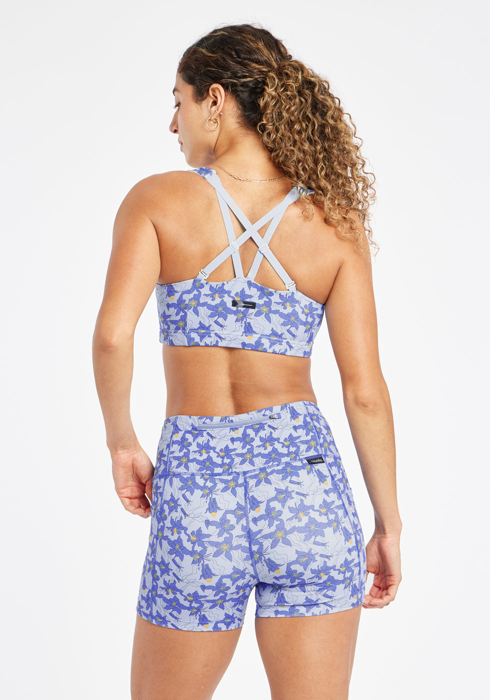 Woman wearing blue with blue floral print sports bra in size 6, alternate back view