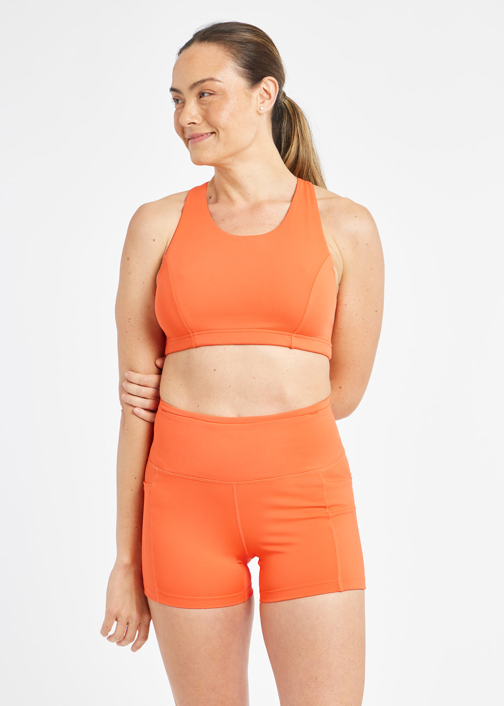 Woman wearing orange sports bra in size 6, alternate front view