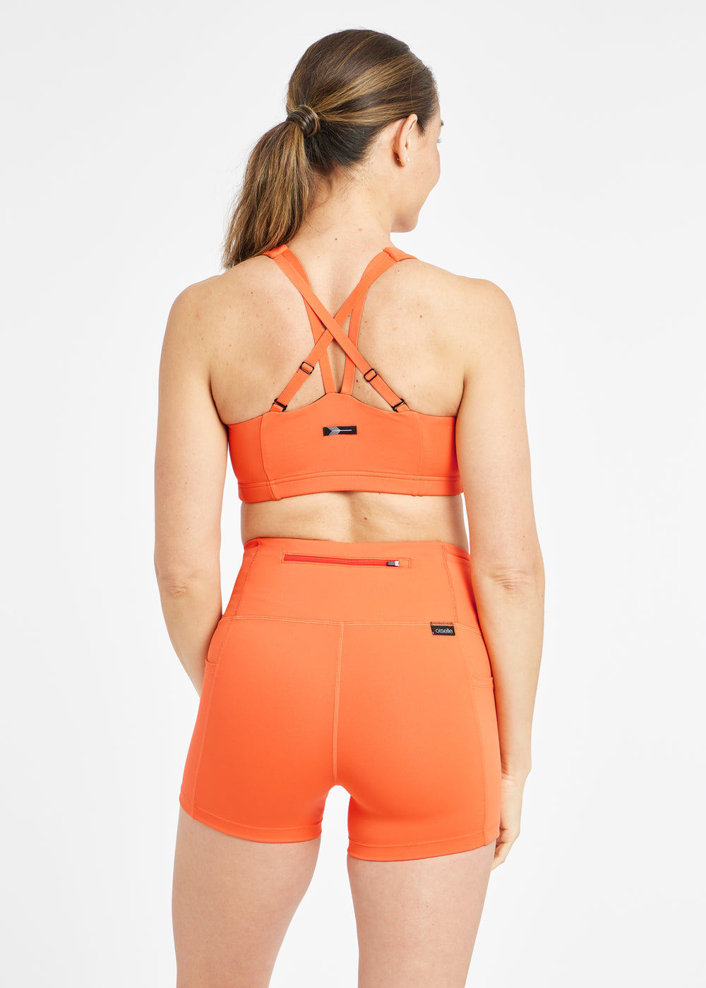 Woman wearing orange sports bra in size 6, alternate back view