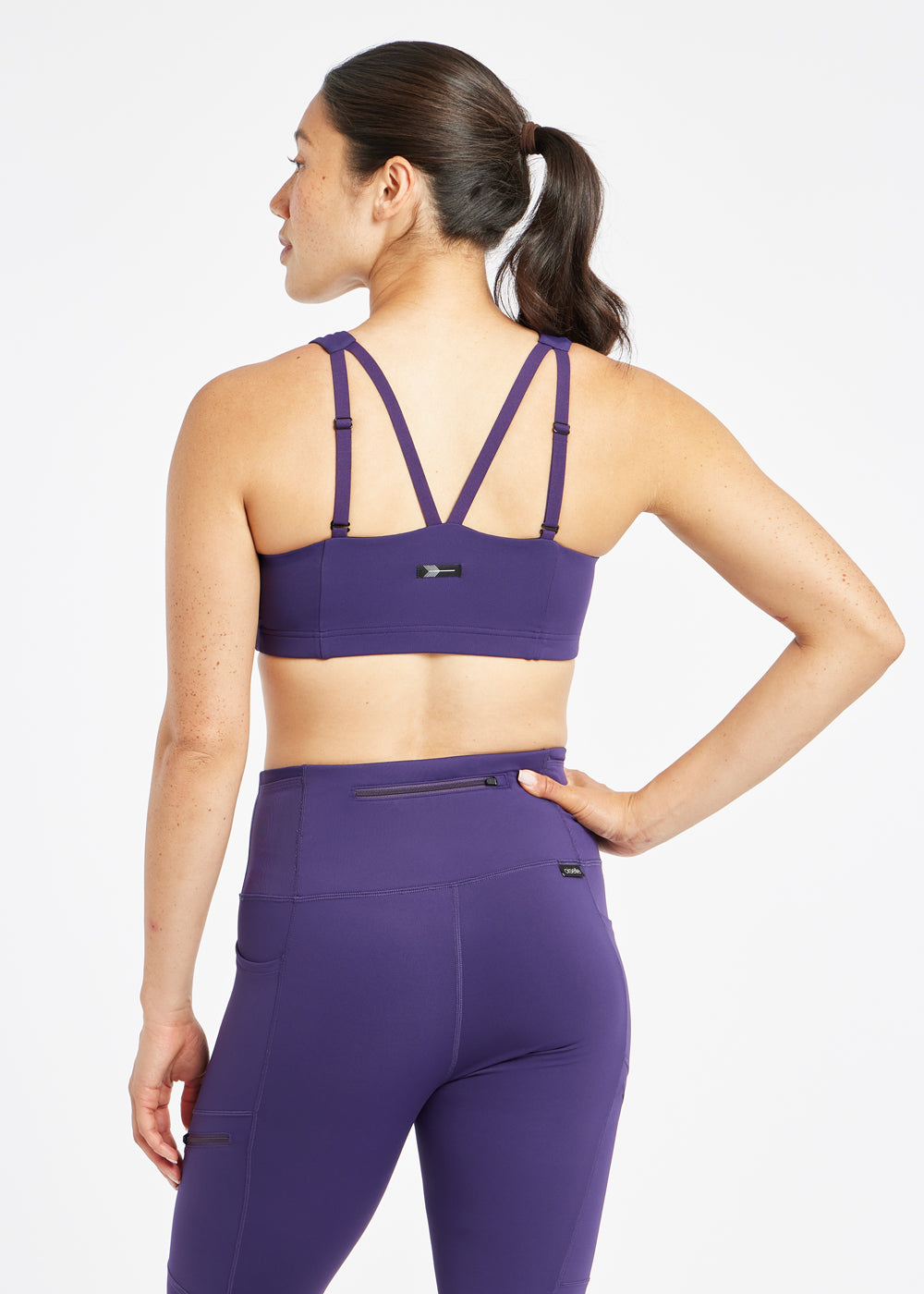 Woman wearing purple sports bra in size 6, back view
