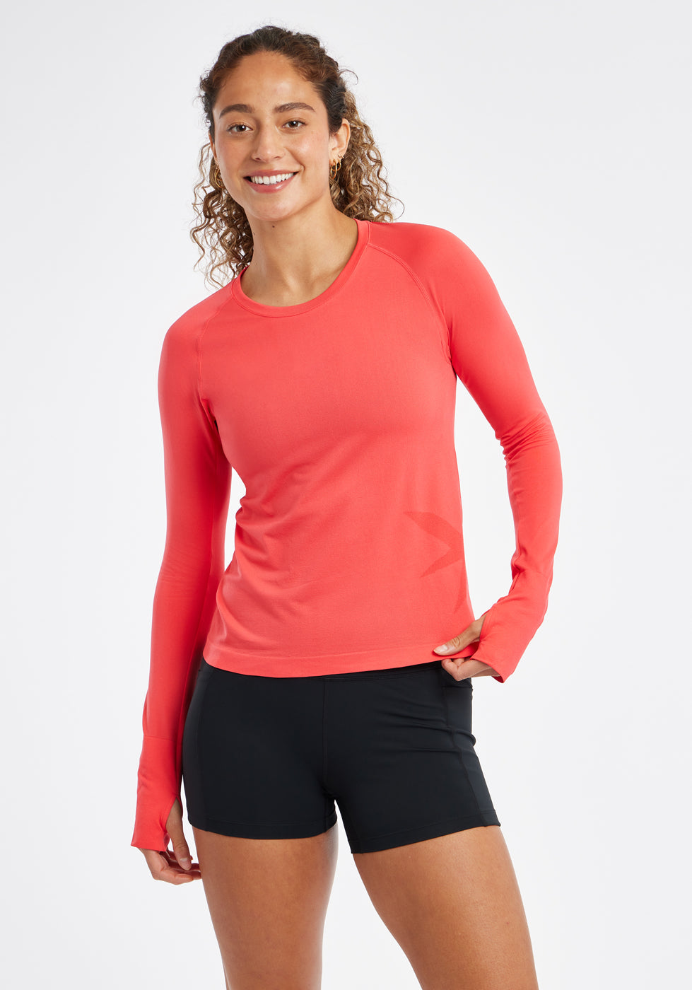 Woman wearing a red orange running long sleeve and black compression shorts, second alternate front view
