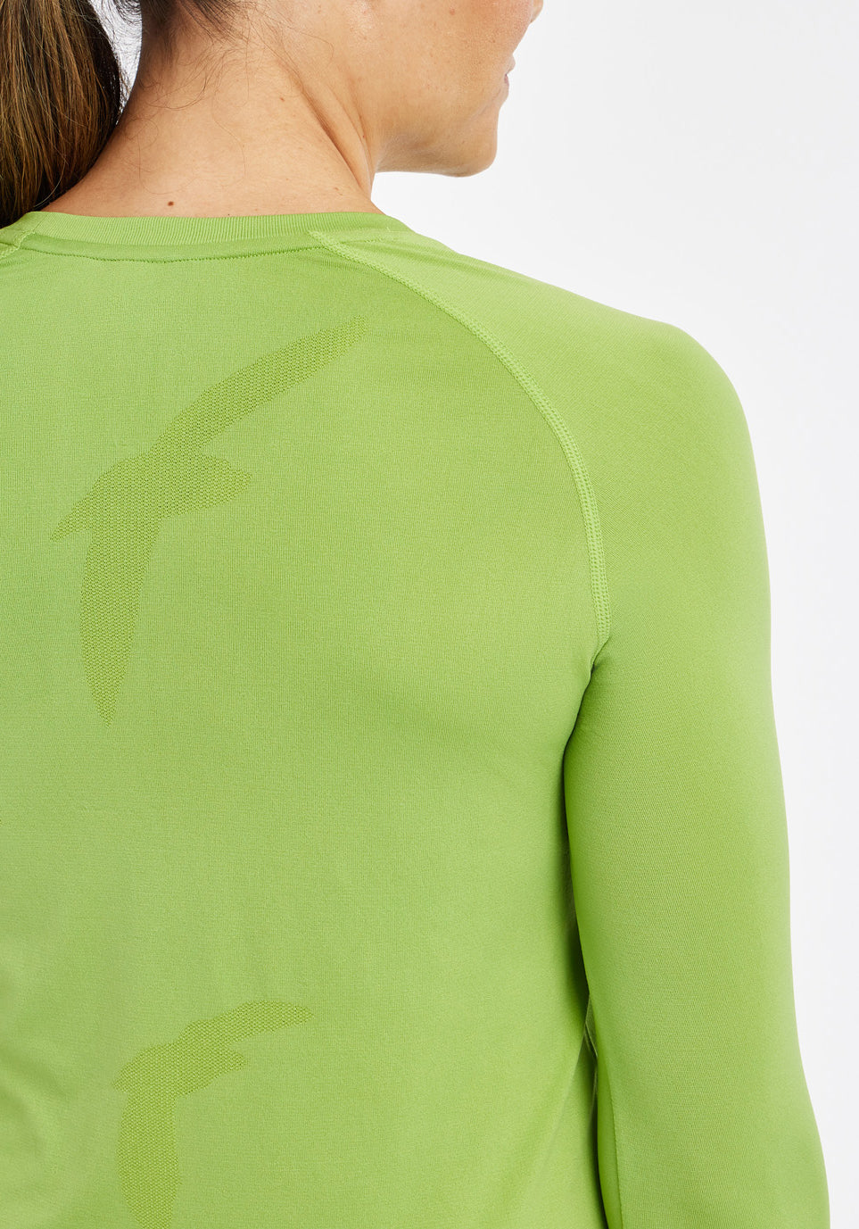 Woman wearing a green running long sleeve, close up of bird details on shirt