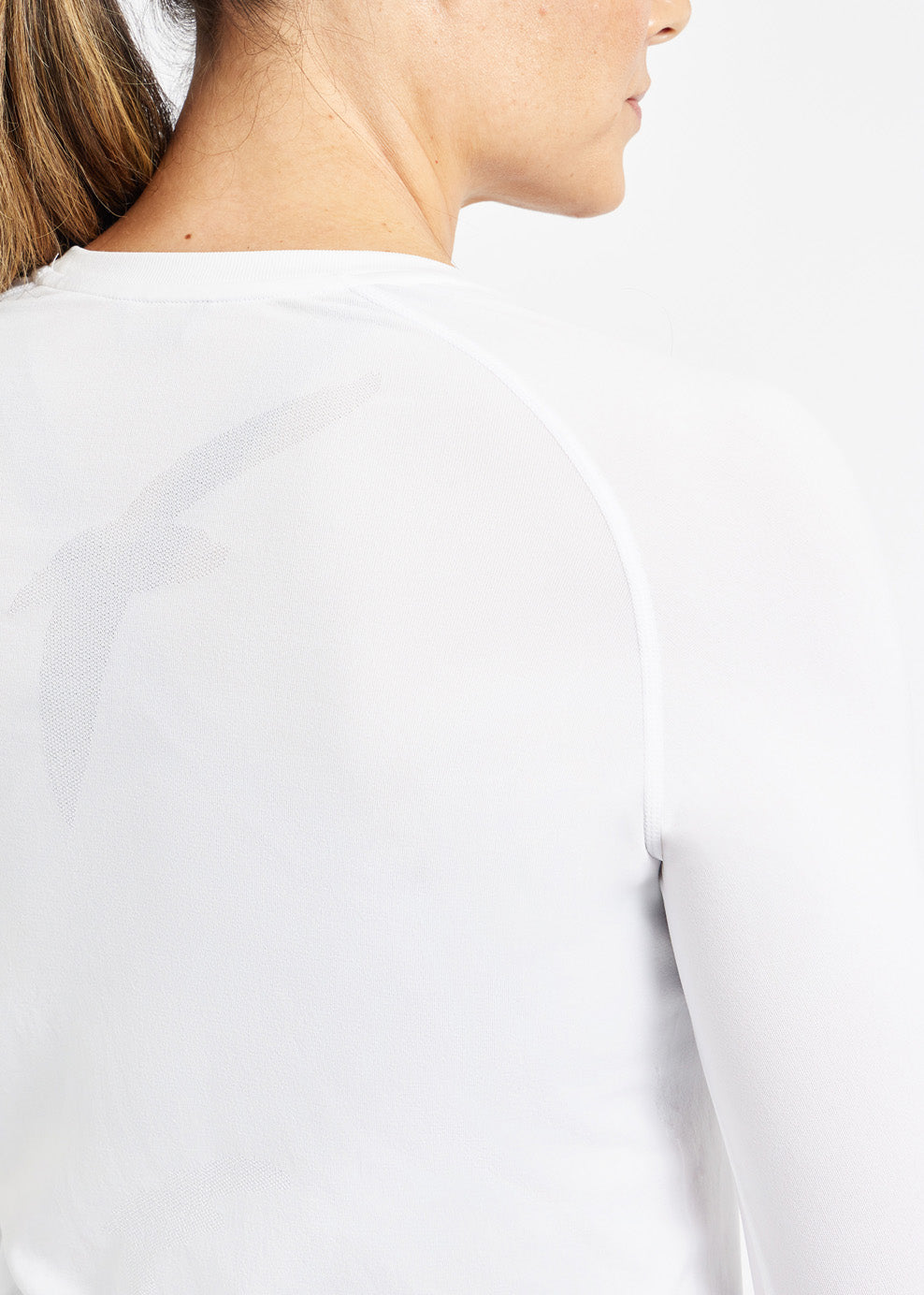 Woman wearing a white running long sleeve, close up of bird details on shirt