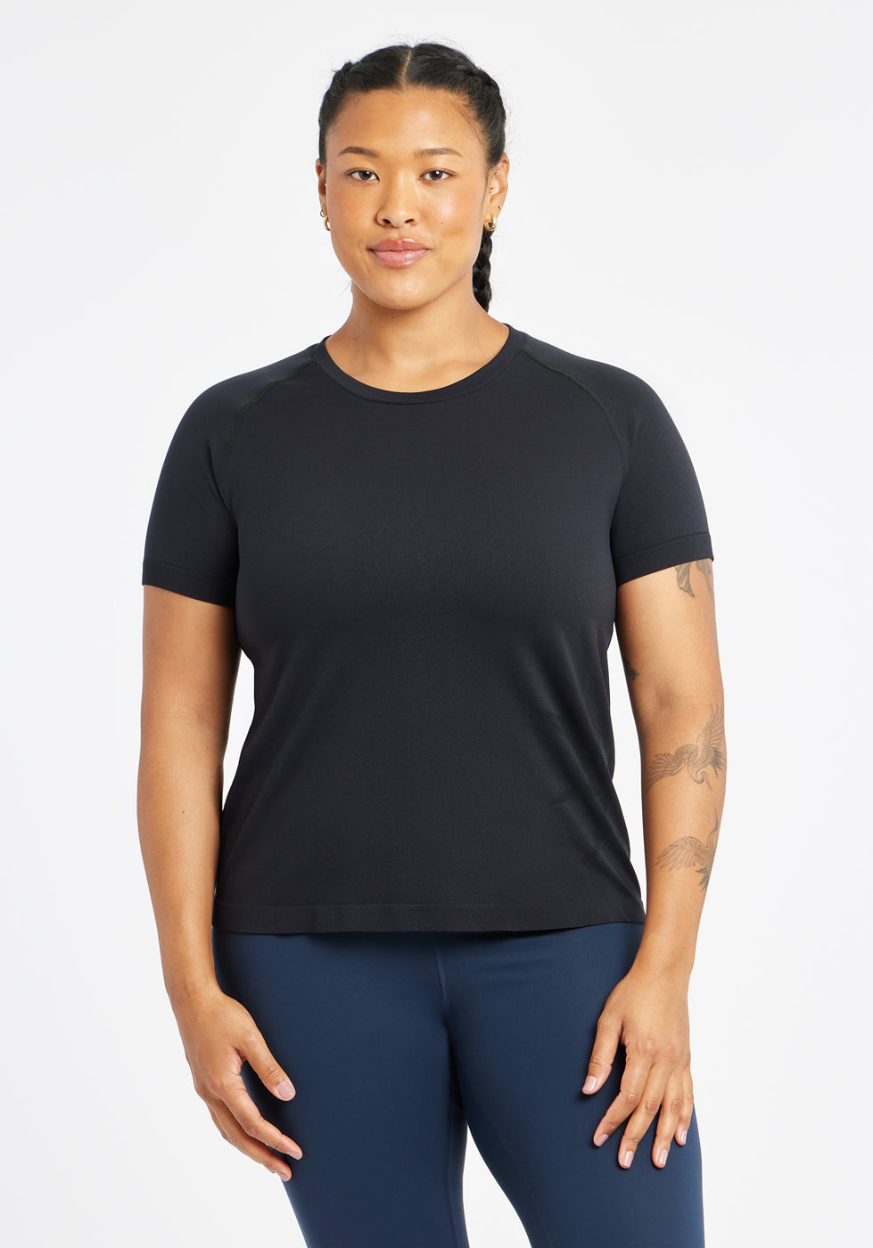 Woman wearing a black running short sleeve and navy compression tights, front view