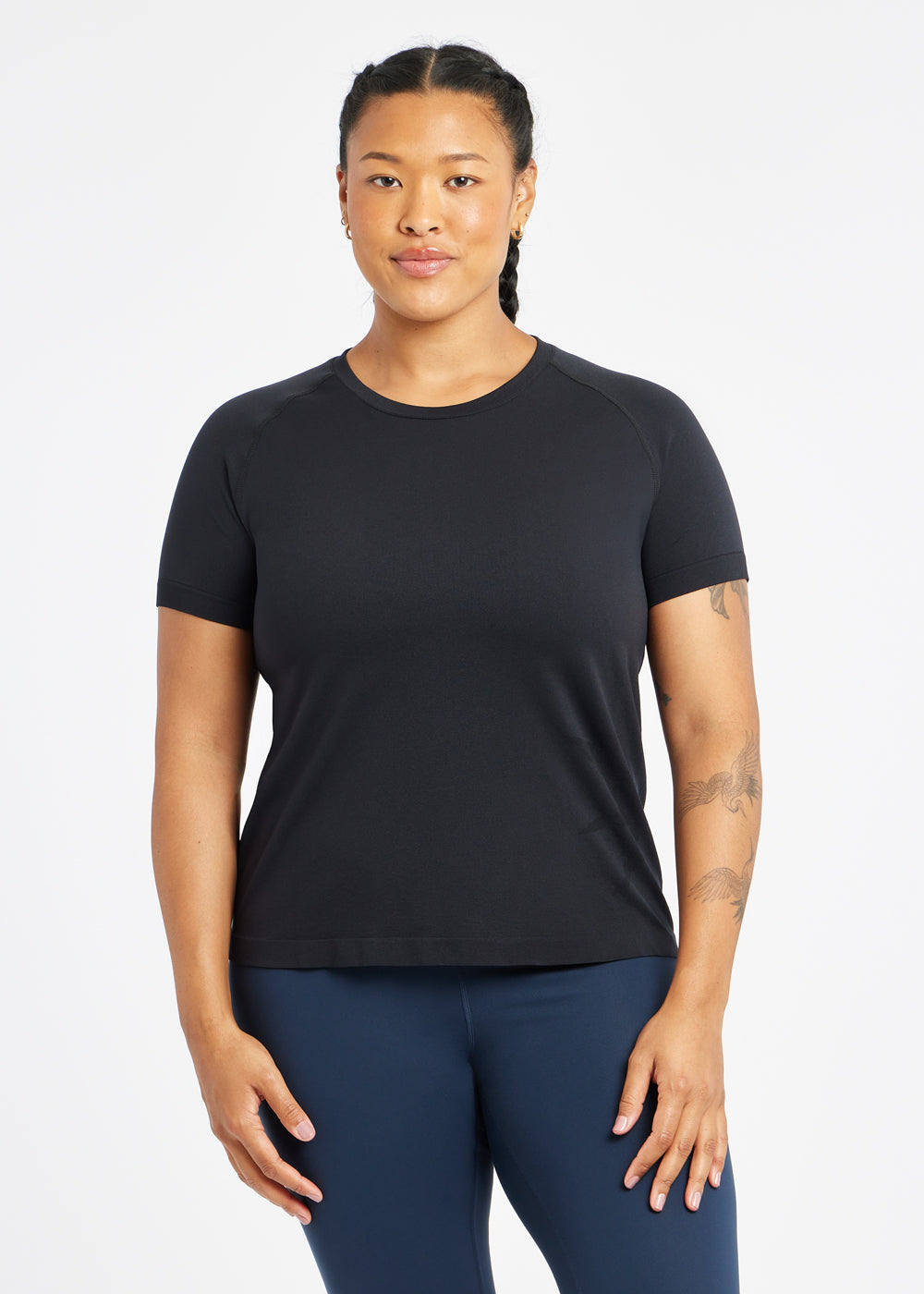 Woman wearing a black running short sleeve and navy compression tights, front view