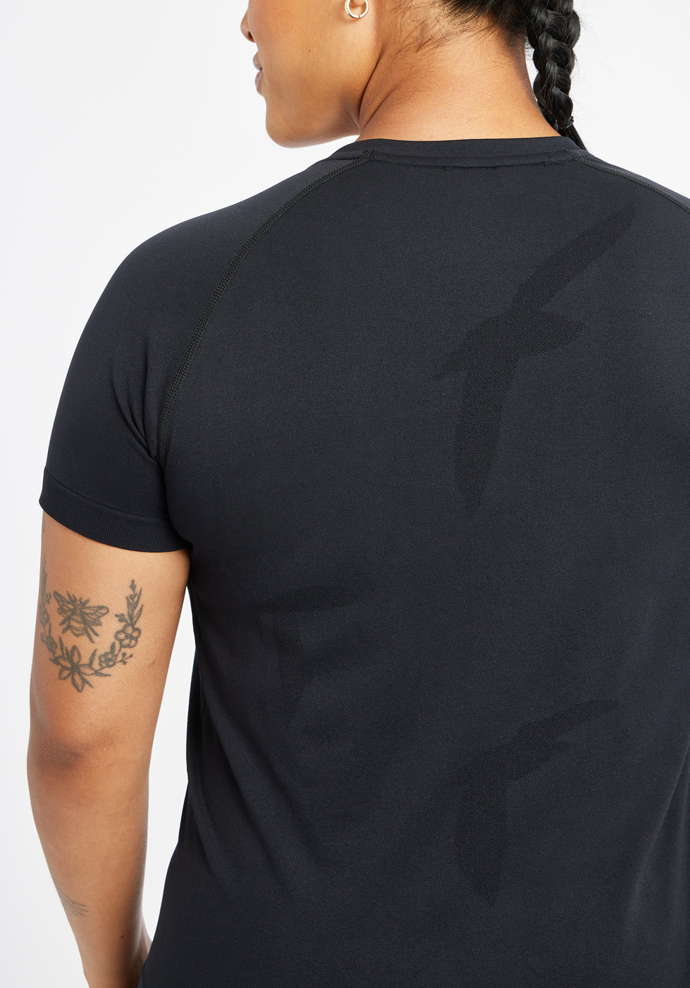 Woman wearing a black running short sleeve, close up of bird details on shirt