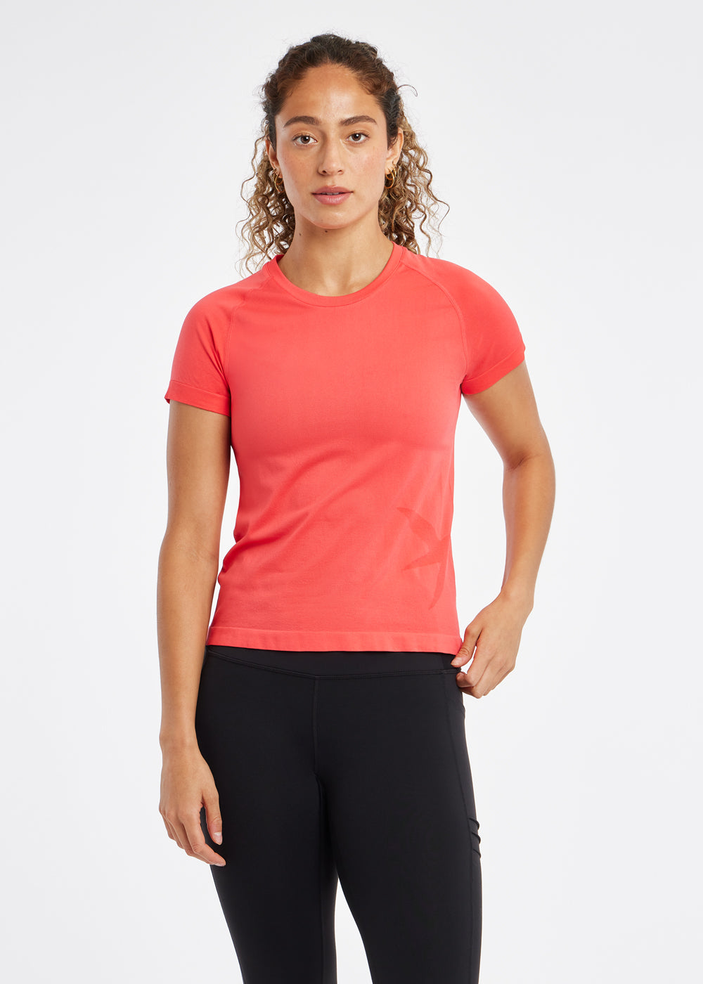 Woman wearing a red orange running short sleeve and black compression tights, front view