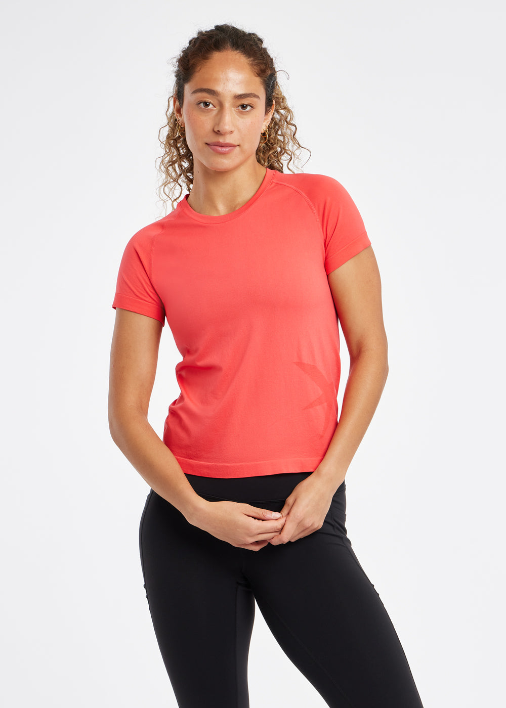 Woman wearing a red orange running short sleeve and black compression tights, alternate front view