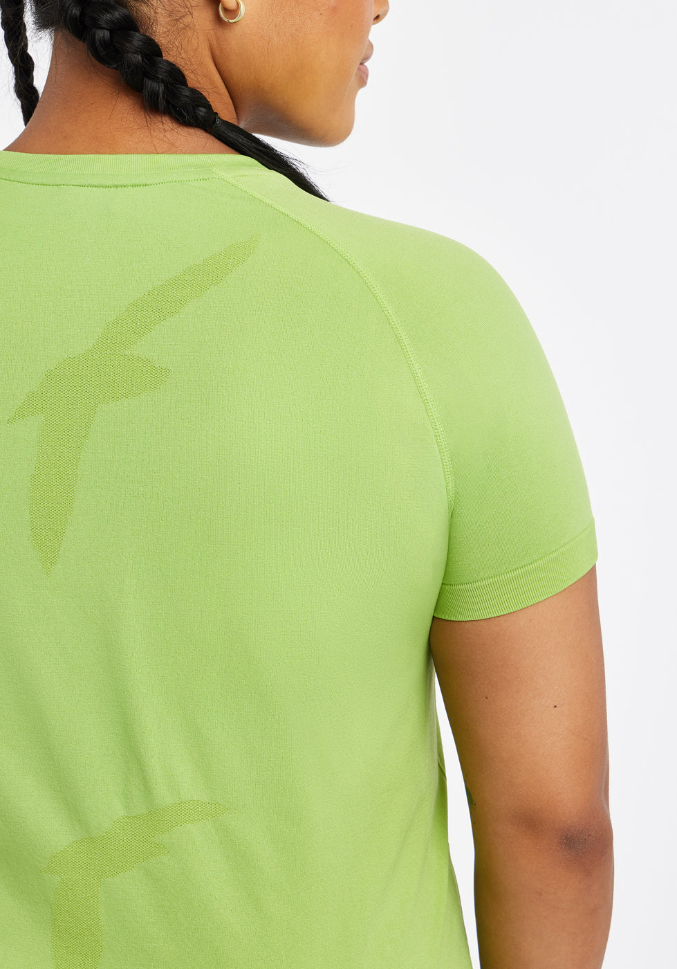 Woman wearing a green running short sleeve, close up of bird details on shirt