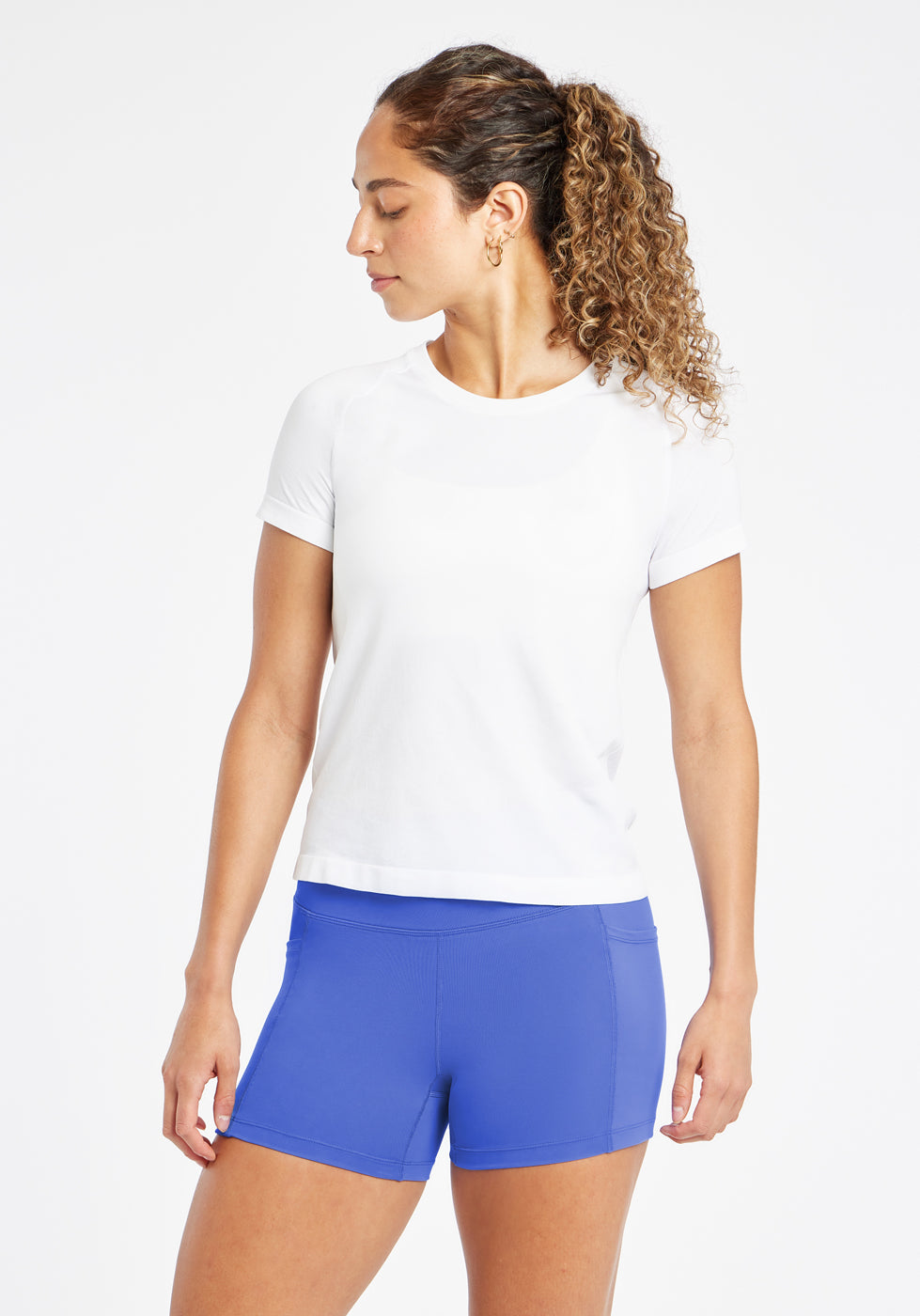 Woman wearing a white running short sleeve and blue compression shorts, second alternate front view