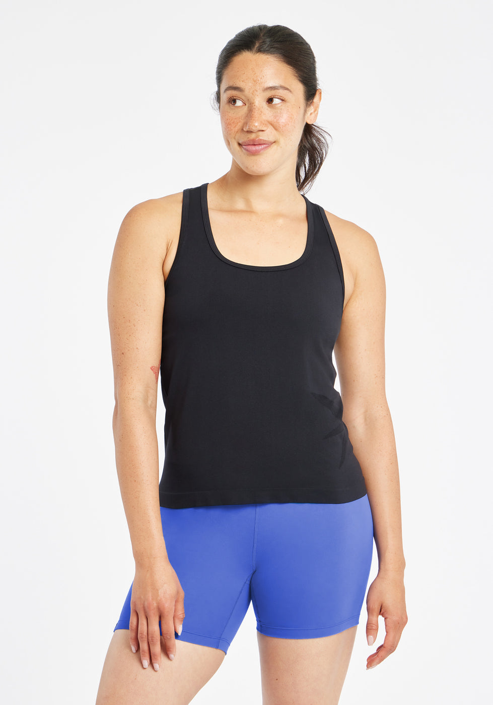 Woman wearing a black running tank top and blue compression shorts, alternate front view