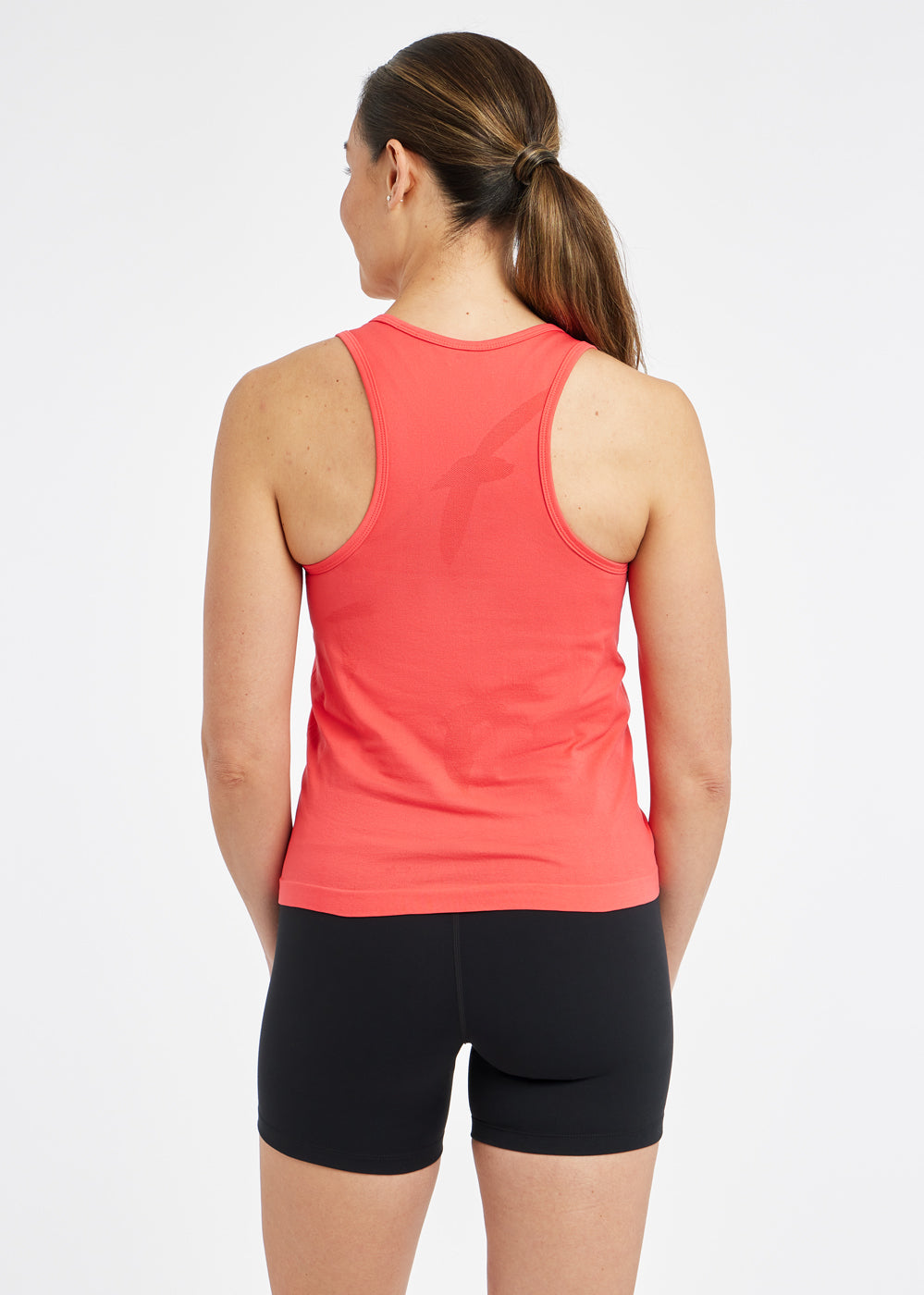 Woman wearing a red orange running tank top and black compression shorts, back view