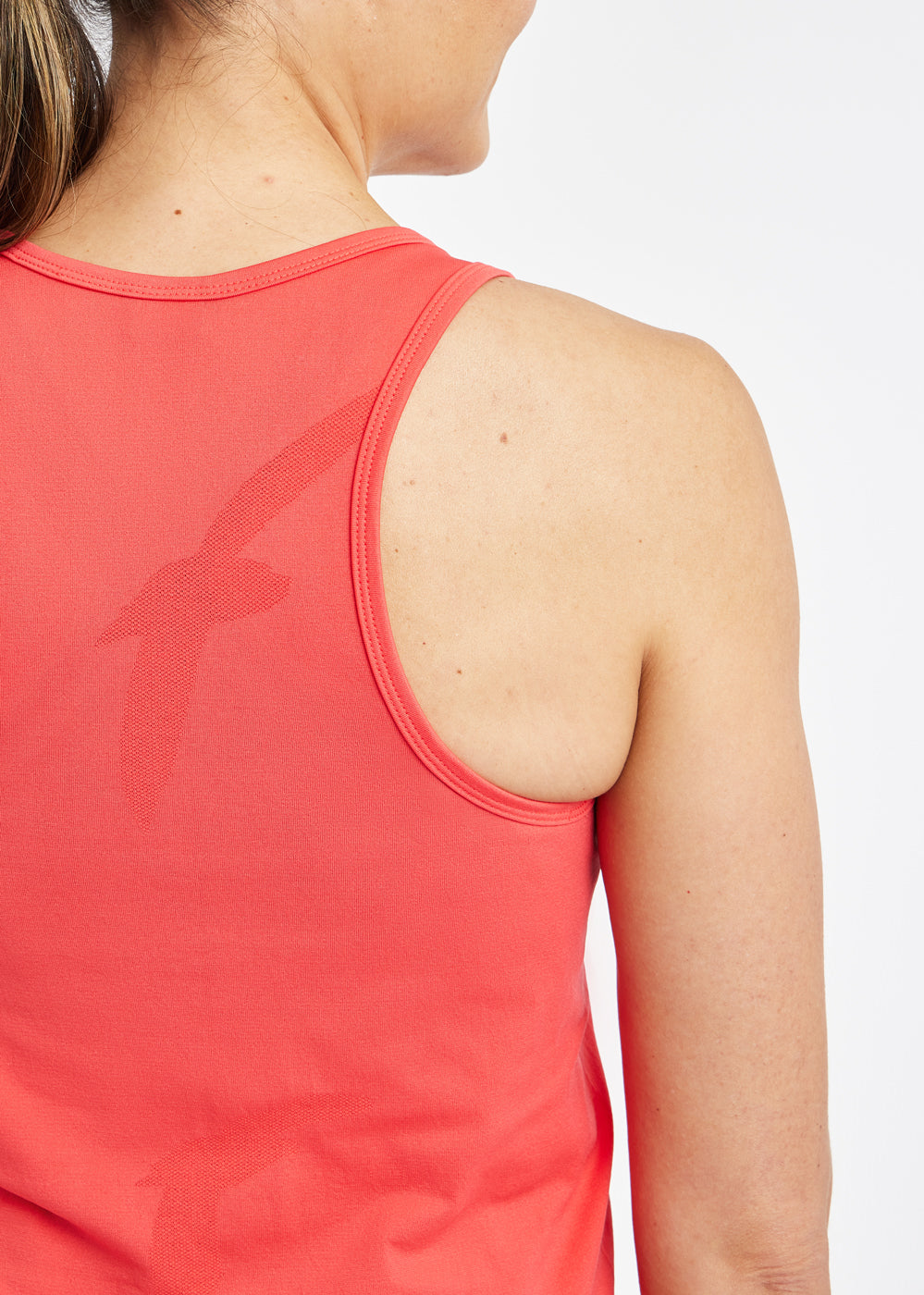 Woman wearing a red orange running tank top, close up of bird details on tank top