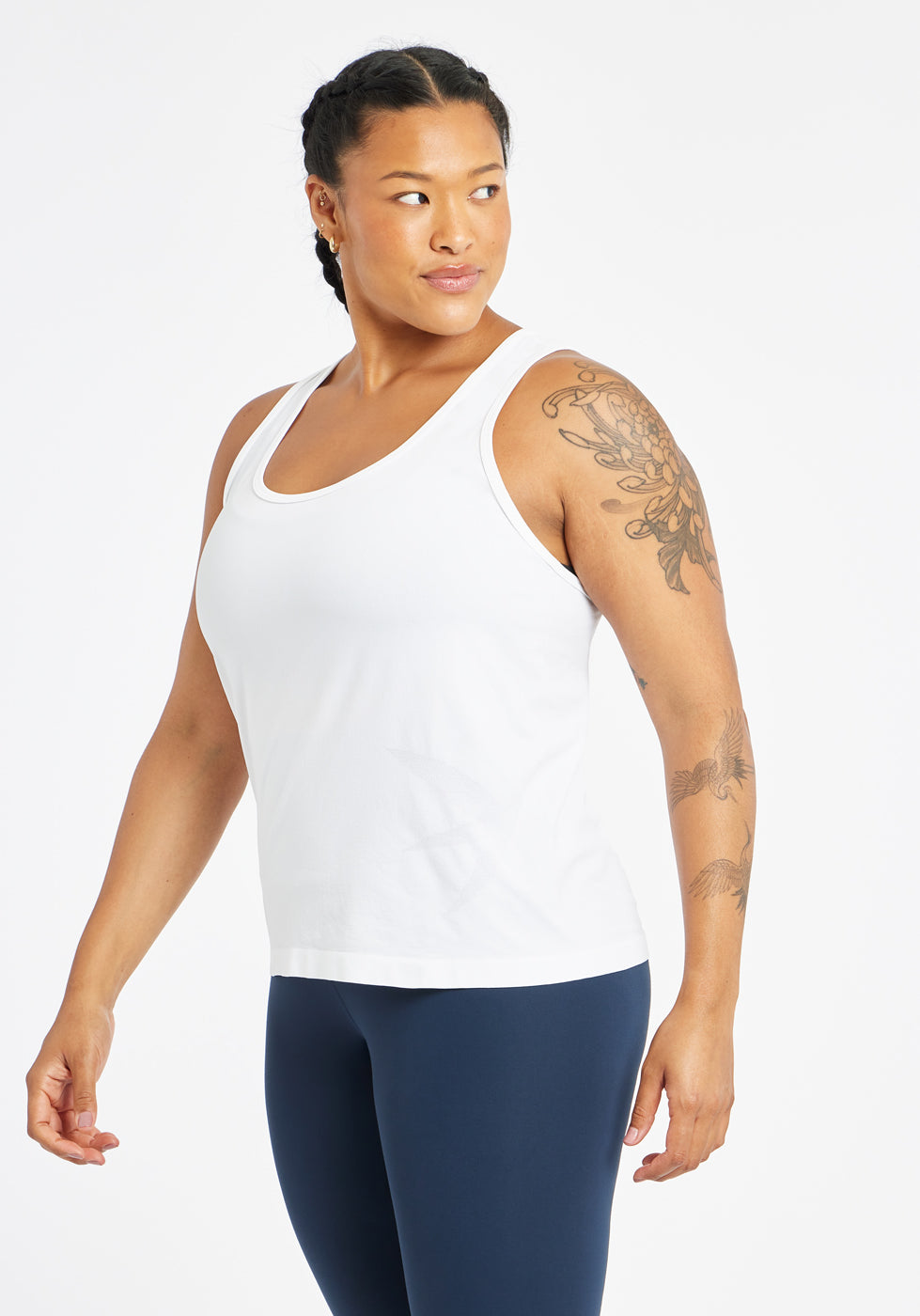 Woman wearing a white running tank top and blue compression tights, side view