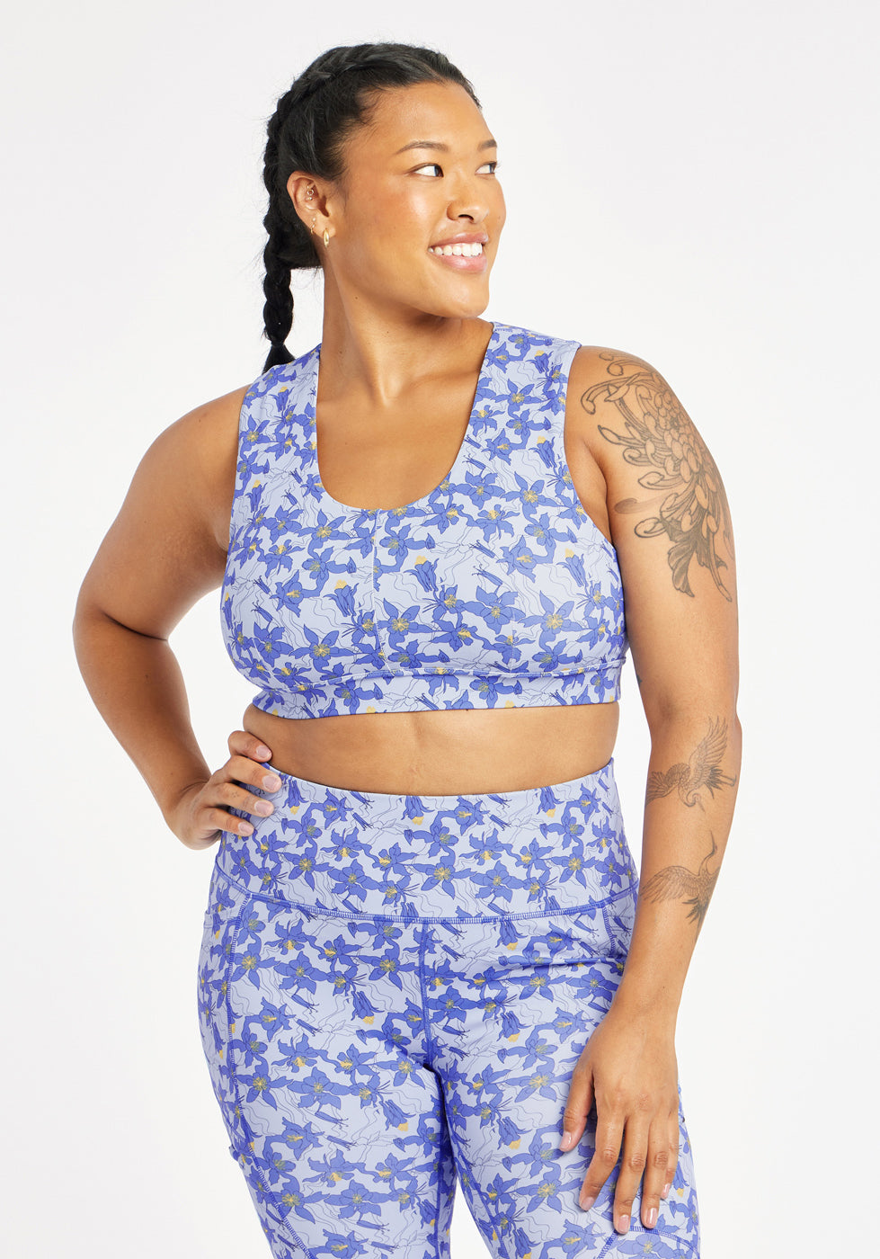 Woman wearing matching blue with blue flower print sports bra and compression shorts in size 12, front view