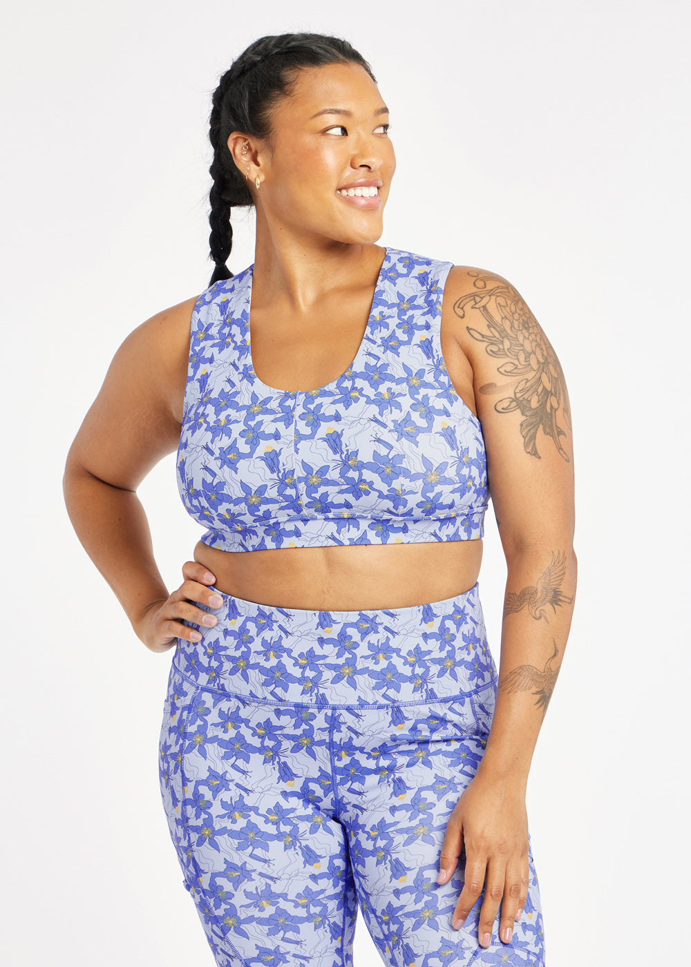 Woman wearing matching blue with blue flower print sports bra and compression shorts in size 12, front view