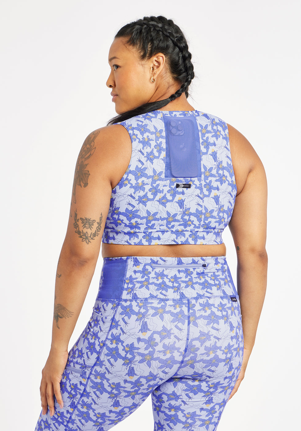 Woman wearing matching blue with blue flower print sports bra and compression shorts in size 12, back view