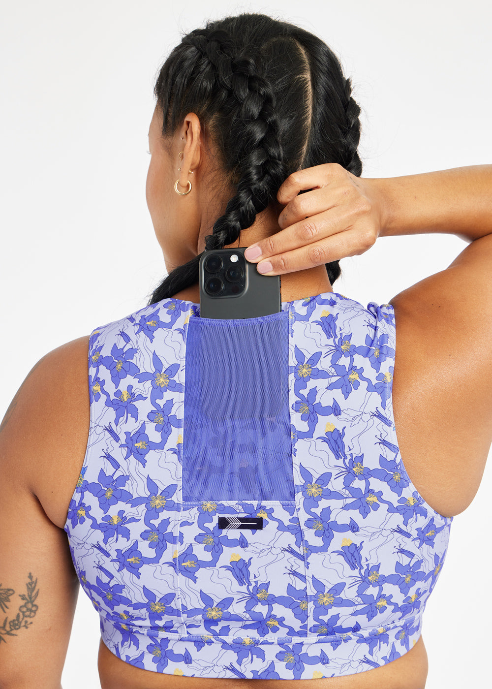 Woman wearing blue with blue flower print sports bra, close up view of phone pocket in the back