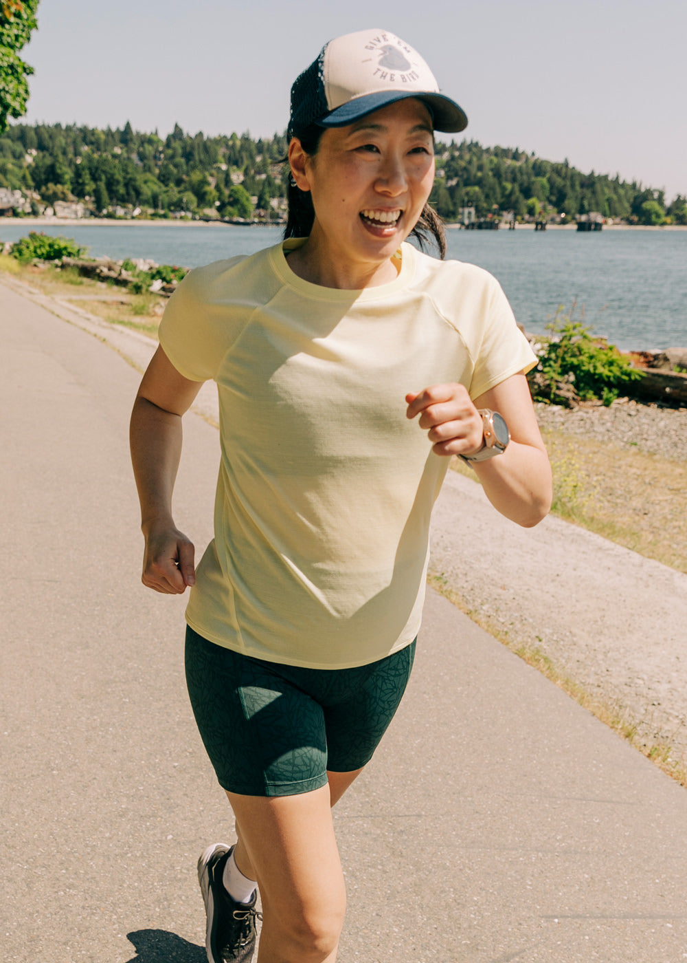 Flyout Wool Classic Short Sleeve in Rise light yellow, woman running on lake path