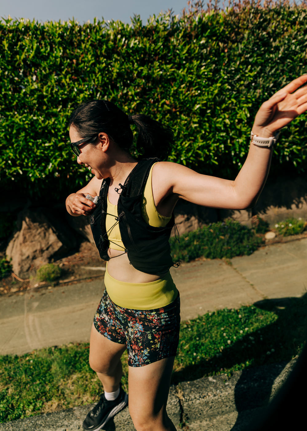 Woman running outside in High Rise Roga 4" Running Shorts in Dark Floral print and hydration vest