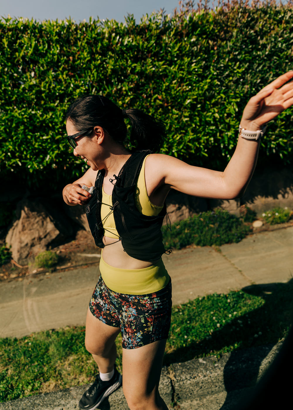 Woman running outside in High Rise Roga 4" Running Shorts in Dark Floral print and hydration vest