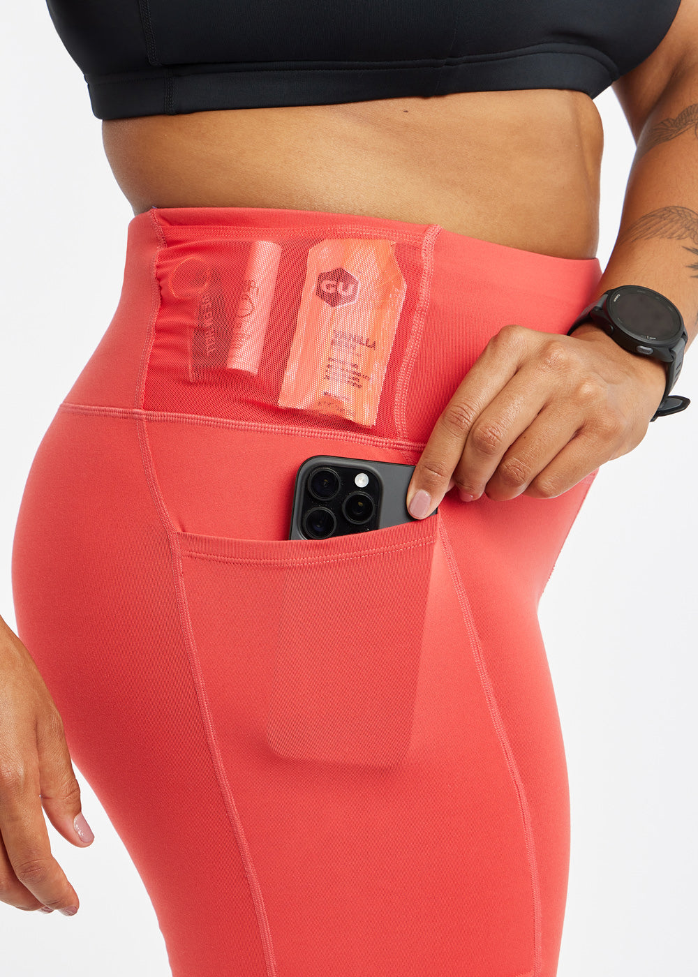 Woman wearing red orange compression shorts, close up of side pockets with accessories