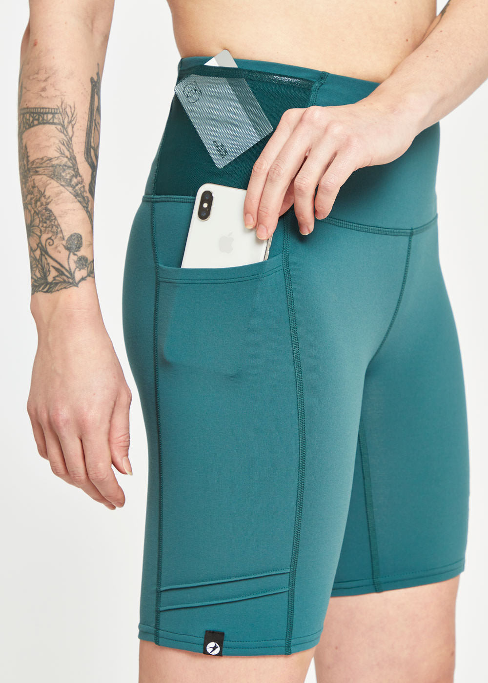 Woman wearing green compression shorts, close up of side pockets with accessories