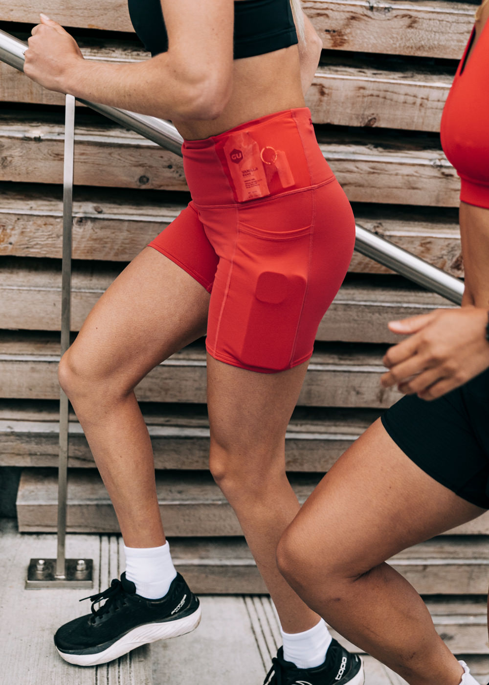 Woman wearing red orange compression shorts, side view running up stairs