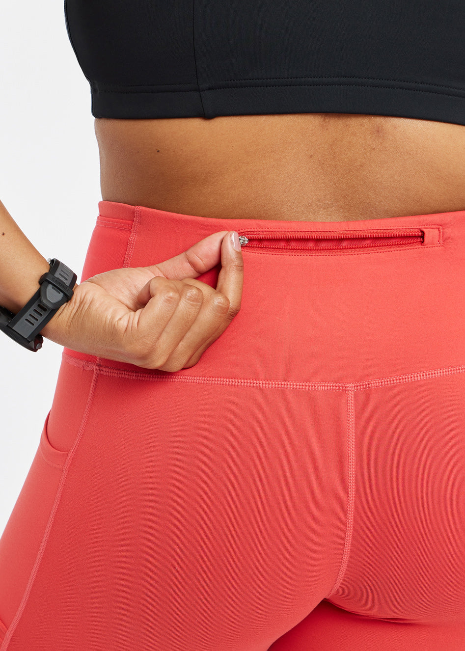 Woman wearing red orange compression shorts, close up of back zipper pocket