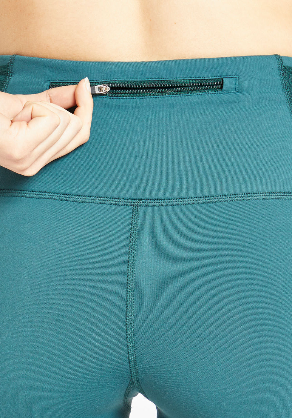 Woman wearing green compression shorts, close up of back zipper pocket