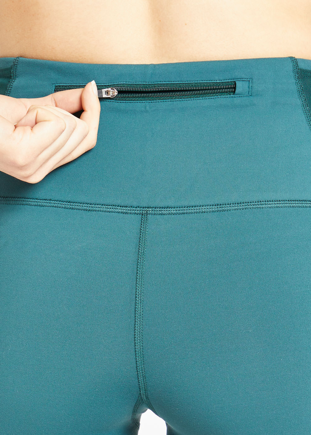 Woman wearing green compression shorts, close up of back zipper pocket