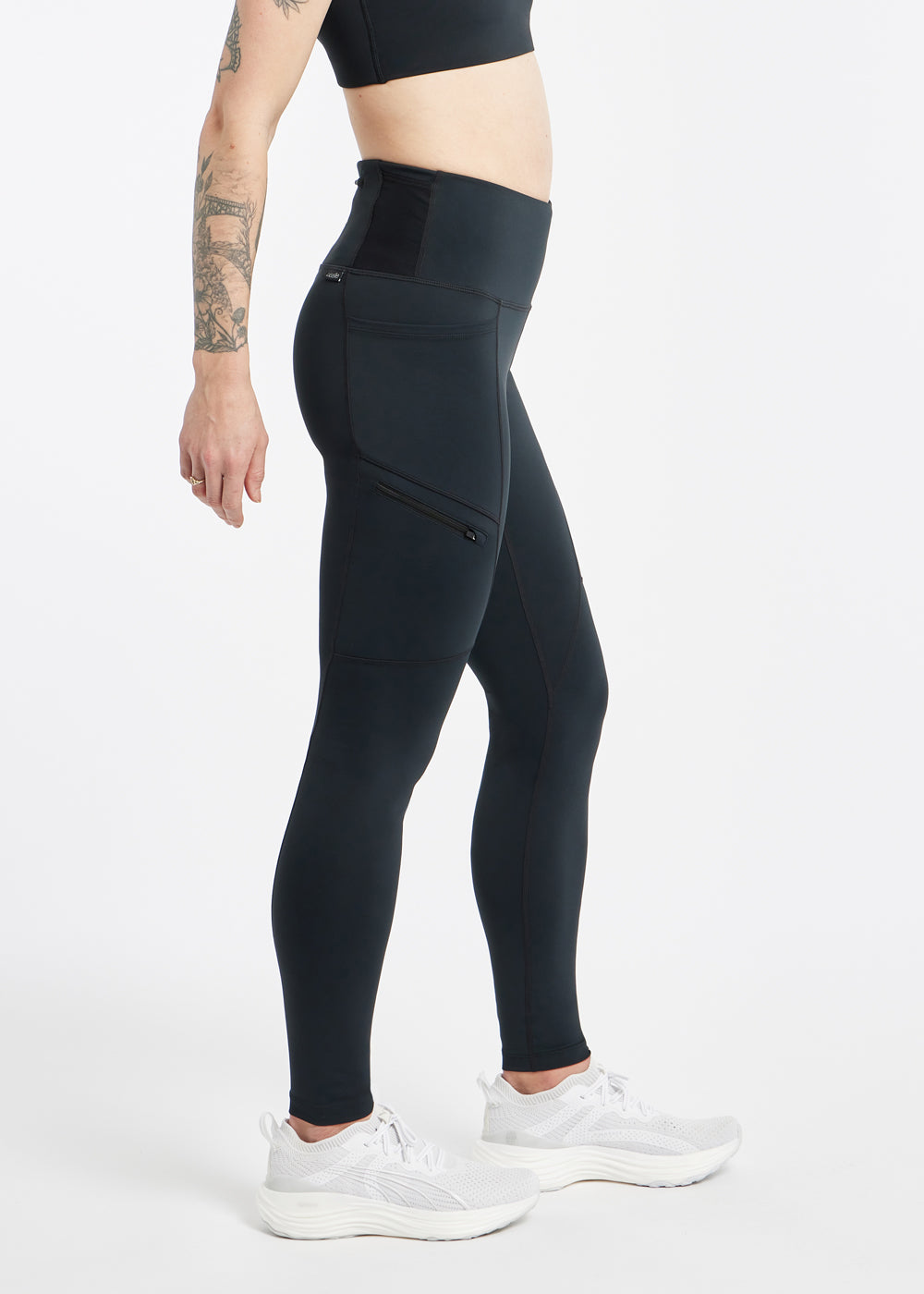 Woman wearing black running tights in size 4, side view