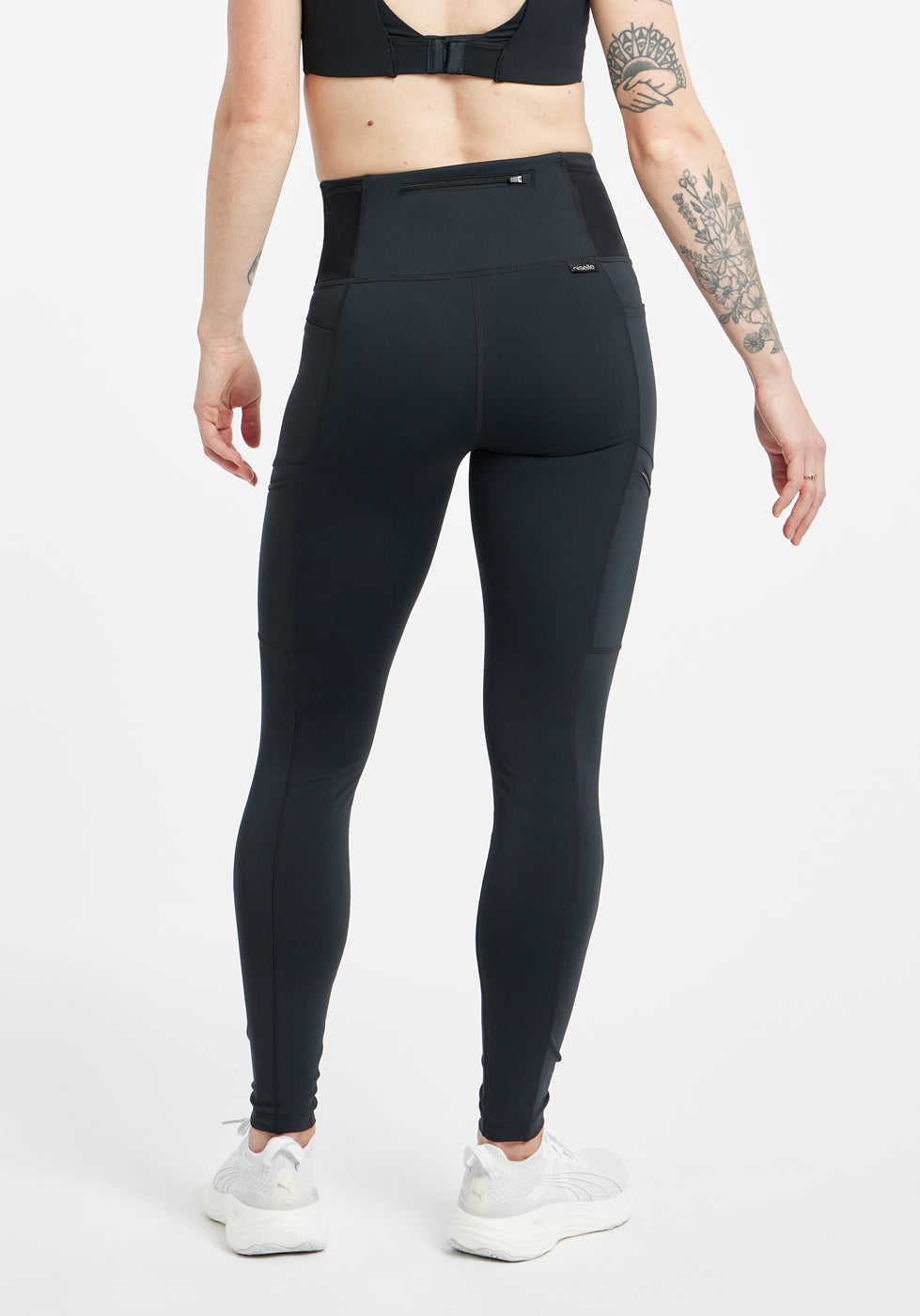 Woman wearing black running tights in size 4, back view