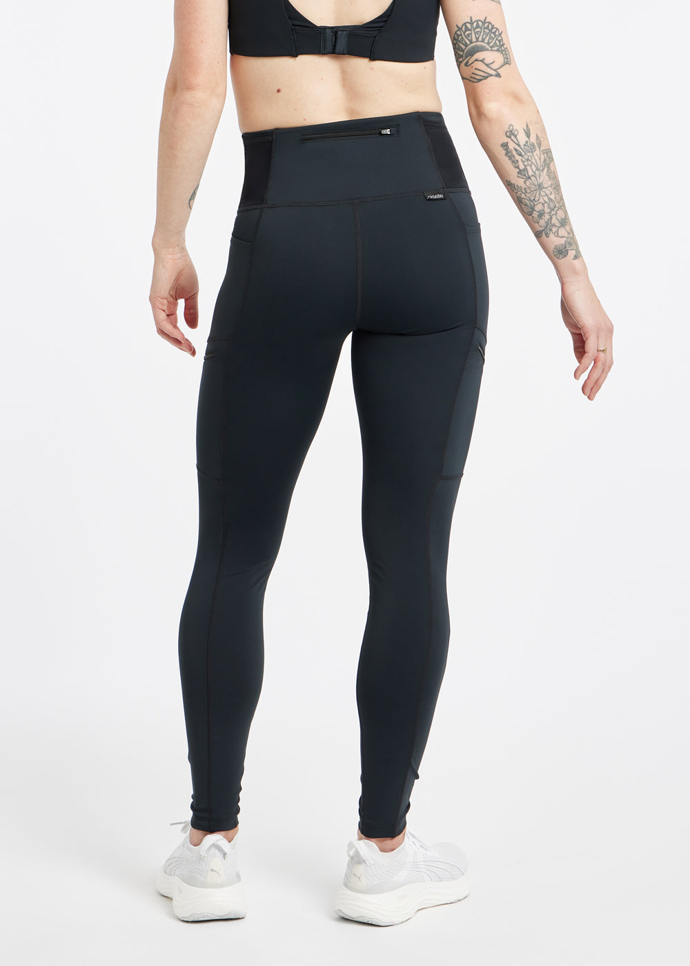 Woman wearing black running tights in size 4, back view