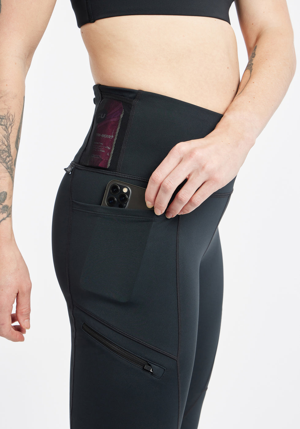 Woman wearing black running tights, close up detail of side pockets