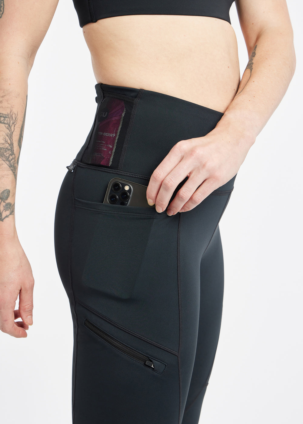 Woman wearing black running tights, close up detail of side pockets