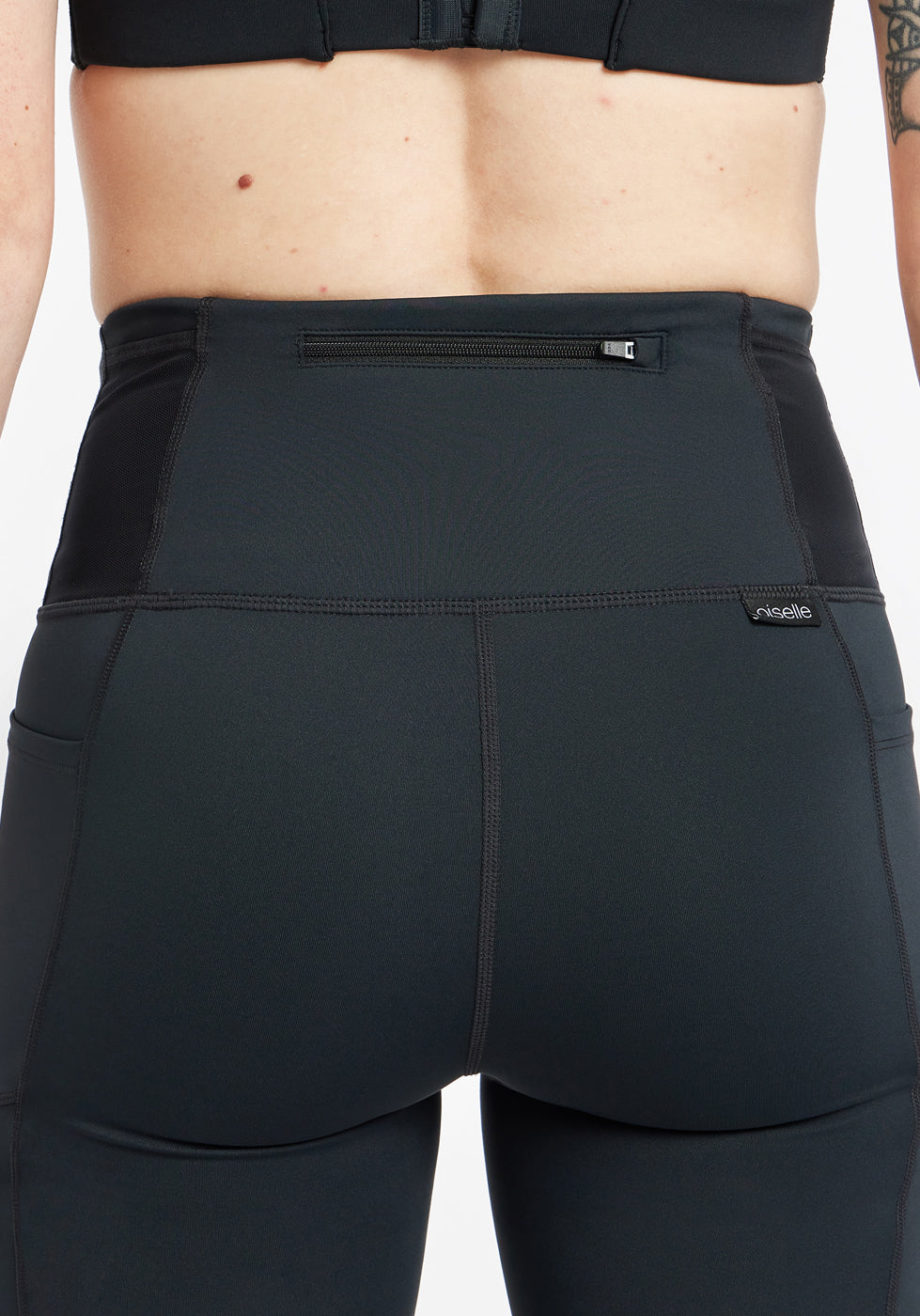 Woman wearing black running tights, close up detail of back zipper pocket