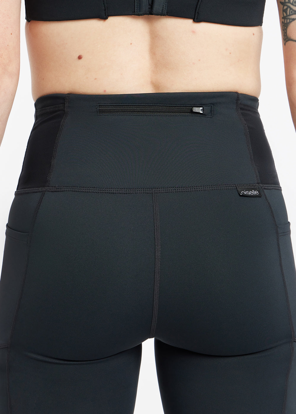 Woman wearing black running tights, close up detail of back zipper pocket
