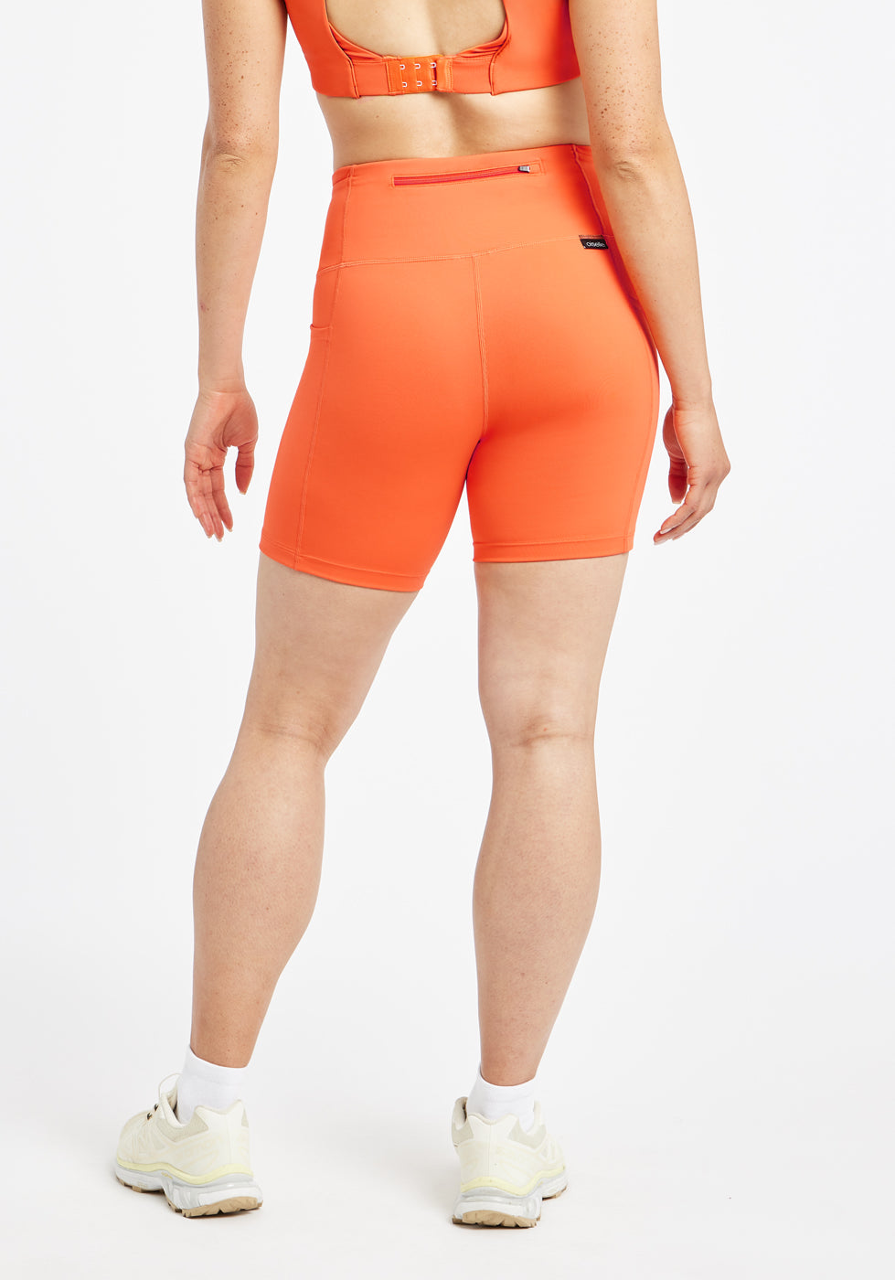 Woman wearing orange compression shorts in size 6, back view