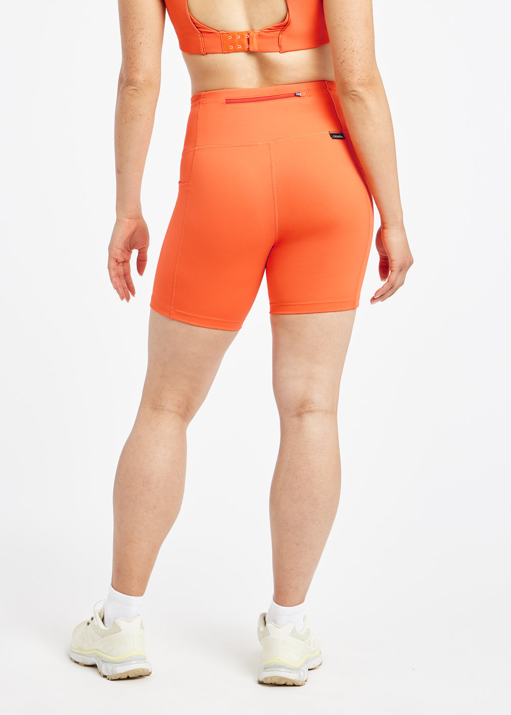 Woman wearing orange compression shorts in size 6, back view
