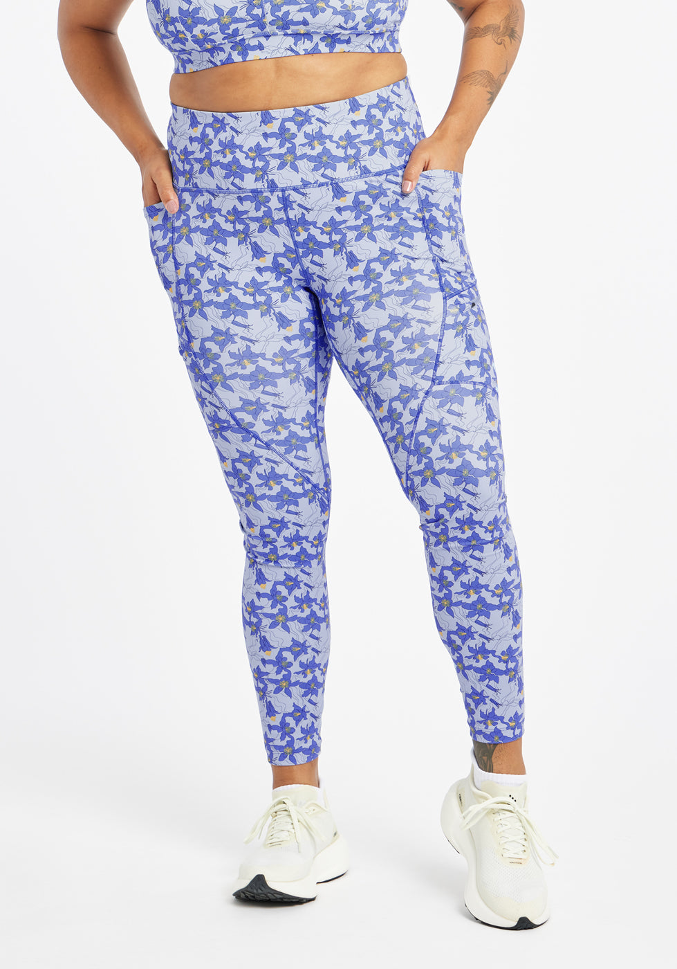 Woman wearing blue with blue flower print running tights in size 12, alternate front view