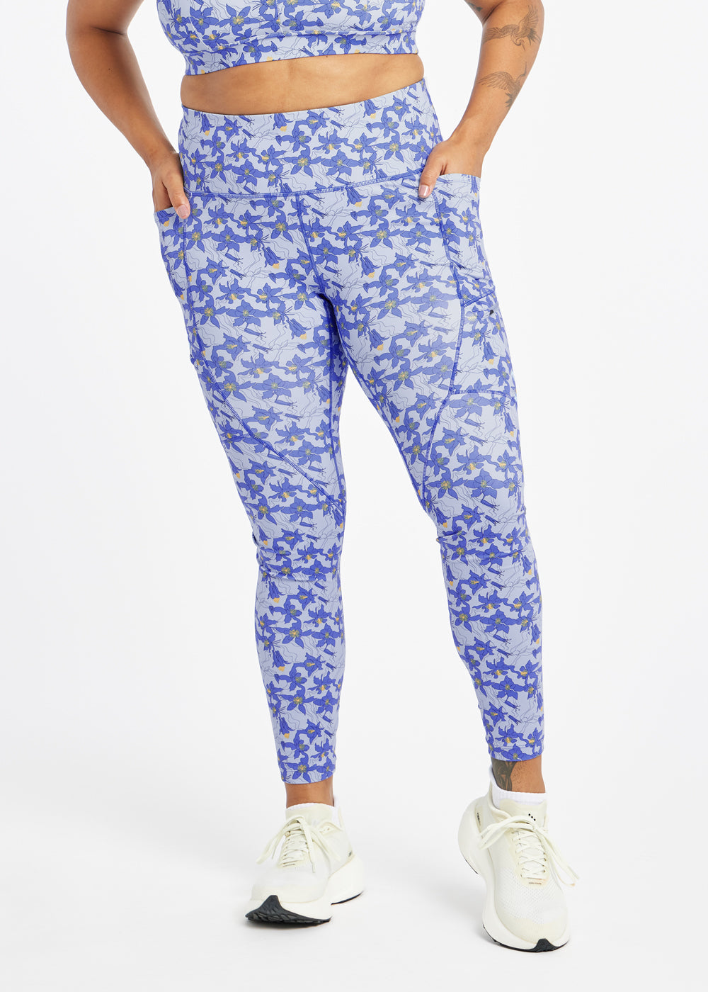 Woman wearing blue with blue flower print running tights in size 12, alternate front view